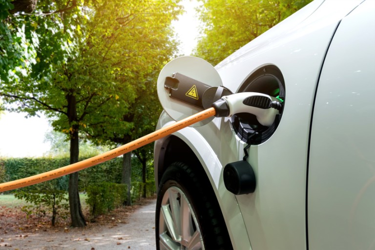 E-Mobility загрузка Orange charge cable stuck into the tank opening of a white car
